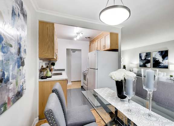 a living room with a dining room table and a kitchen with a refrigerator