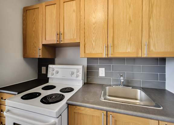 an empty kitchen with a stove sink and cabinets