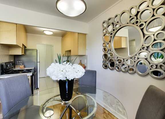 a dining room with a glass table with a vase of flowers