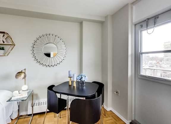 A black table with two chairs and a mirror on the wall.