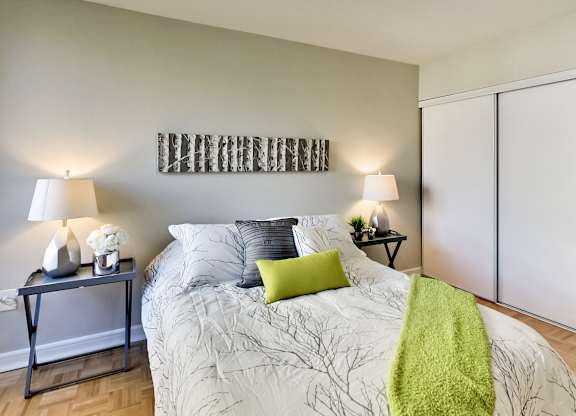 A bedroom with a bed, two lamps, and a green throw.