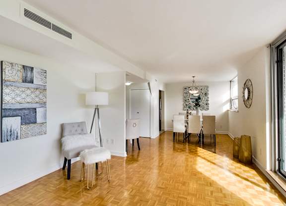 A room with a wooden floor and white walls has a chair and a table in it.