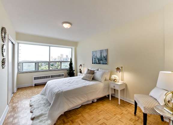 A bedroom with a large bed and a view of the city.