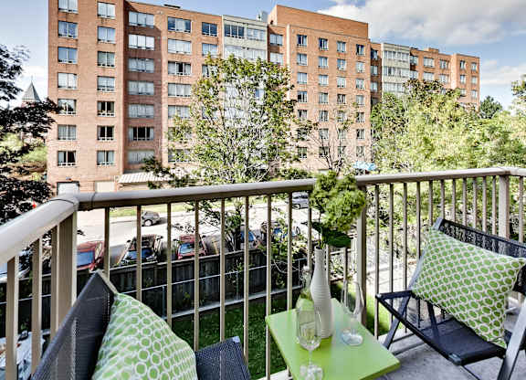 a balcony with two blue chairs and a green table