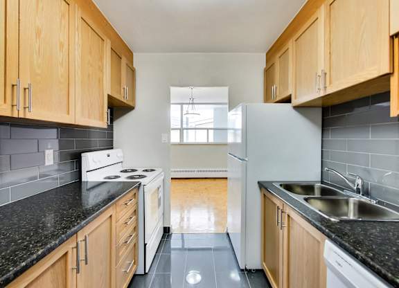 a kitchen with white appliances and black counter tops and wooden cabinets