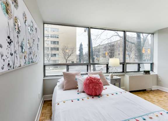 A bedroom with a large bed and a view of the city outside the window.