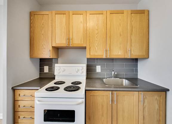 an empty kitchen with white appliances and wooden cabinets