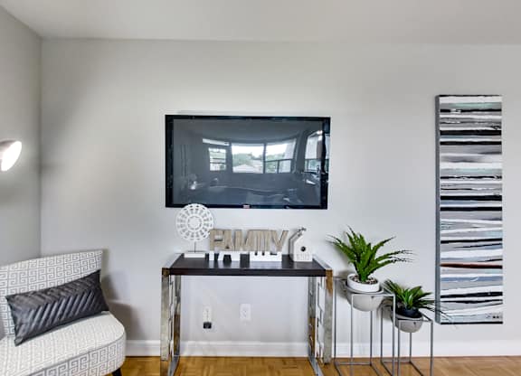 a living room with a tv hanging on the wall and a table with a chair