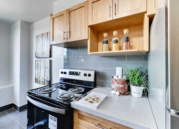 A kitchen with a black stove top oven and wooden cabinets.