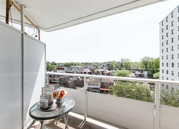 A balcony with a table and chairs overlooking a cityscape.