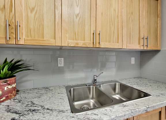 A kitchen with a granite countertop and wooden cabinets.