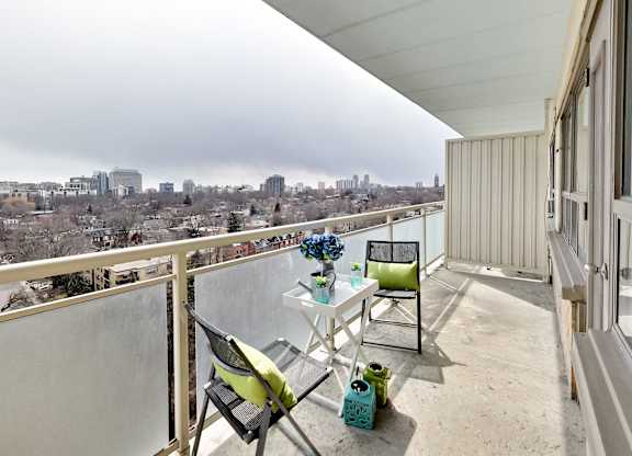 A balcony with a table and chairs overlooking a city.