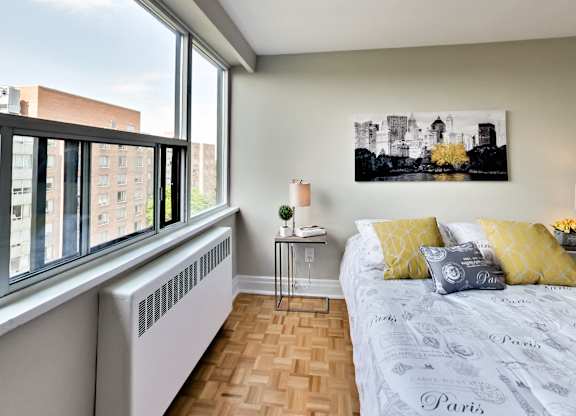 a bedroom with a large window and a bed with yellow pillows