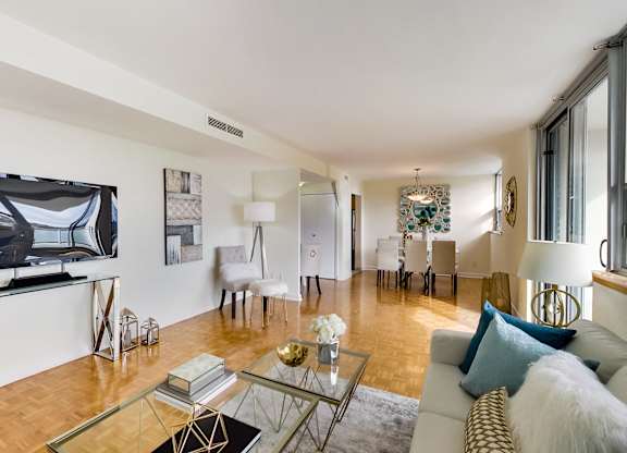 A living room with a glass coffee table and a white couch.