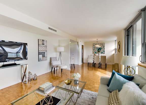 A living room with a glass coffee table and a white couch.