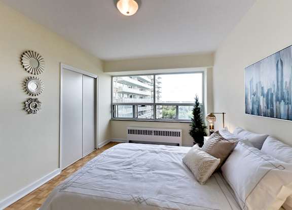 A bedroom with a large bed and a window overlooking a cityscape.