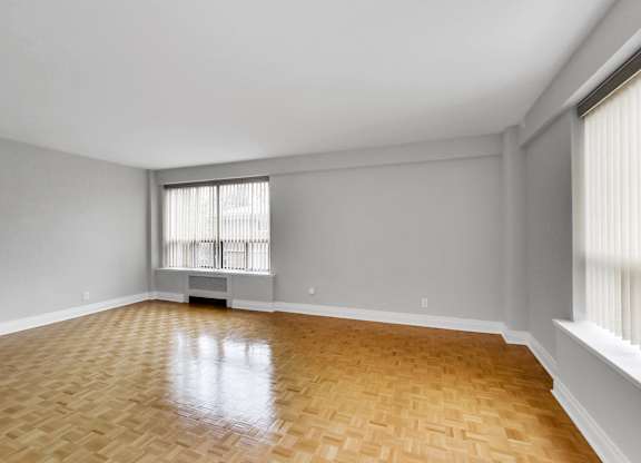 an empty living room with wood flooring and a window