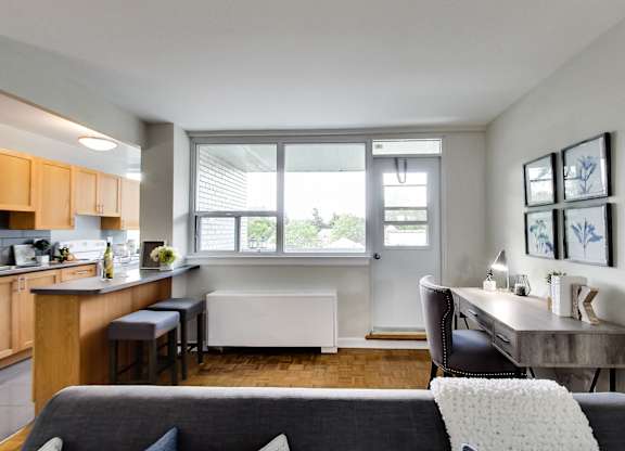 a living room with a couch and a table and a kitchen with a window