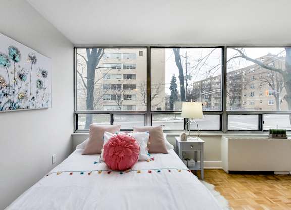 A bedroom with a large bed and a large window overlooking a snowy landscape.
