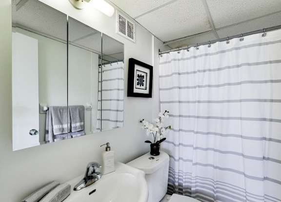 A white sink with a mirror above it and a towel hanging on the wall.