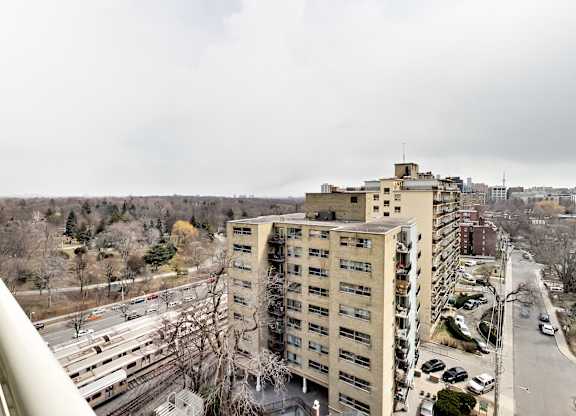 A view of a city from a high vantage point, with a large building in the foreground and a highway in the background.