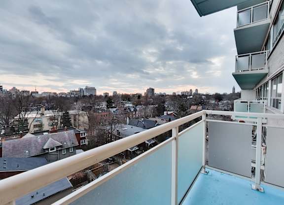 A balcony overlooks a residential area with houses and trees.