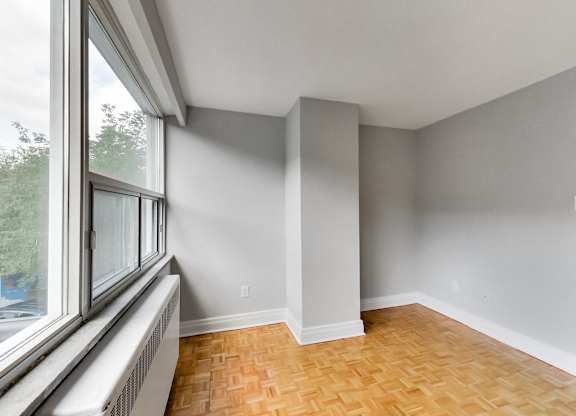 an empty room with a large window and wood flooring