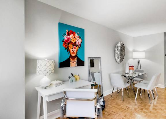 A dining room with a white table and chairs and a painting of a woman with flowers in her hair.