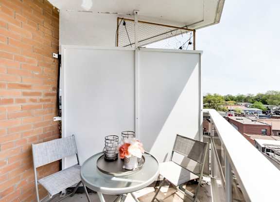 A table with chairs and a vase on a balcony.