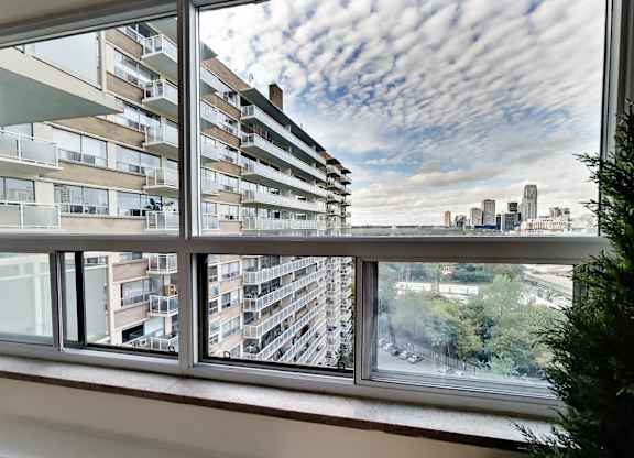 A view from a window of a cityscape with buildings and cars.