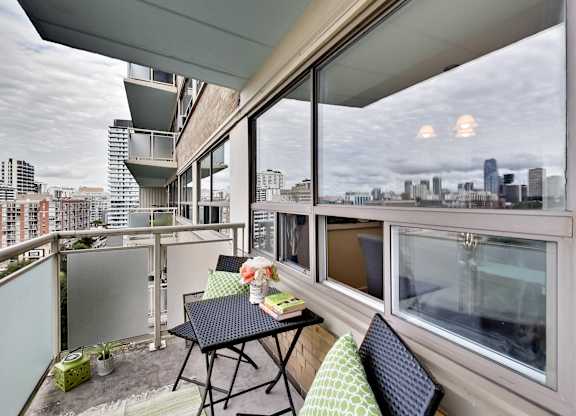 A balcony with a table and chairs overlooking a city skyline.