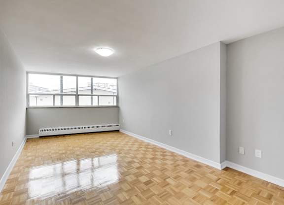 an empty living room with wood flooring and a window