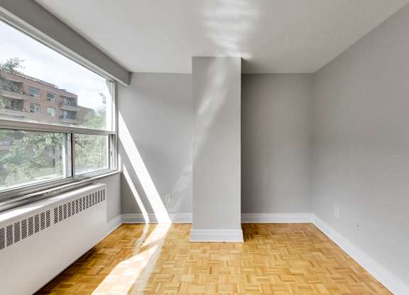 an empty living room with a large window and wood flooring