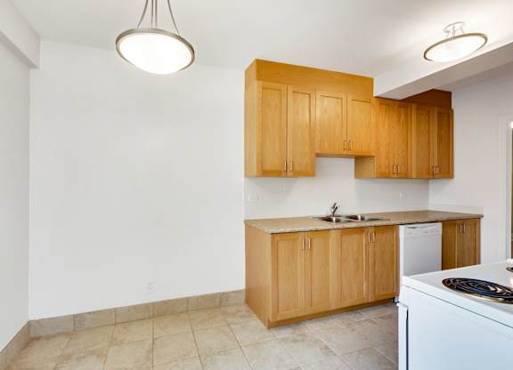 an empty kitchen with white appliances and wooden cabinets