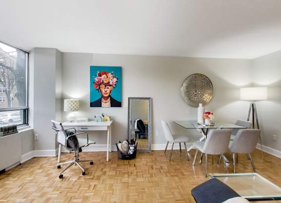 A room with a desk, chairs, and a painting on the wall.