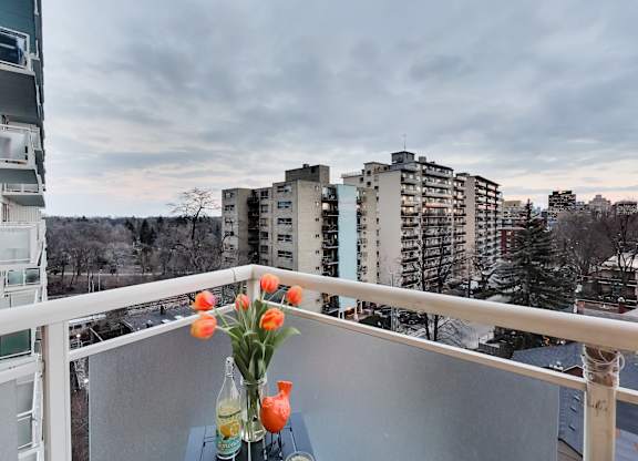 A vase with orange flowers sits on a table on a balcony.