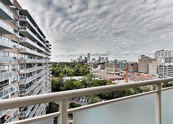 A view of a city from a balcony with a cloudy sky.
