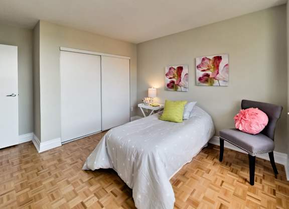 a bedroom with a bed and a chair and a wood floor