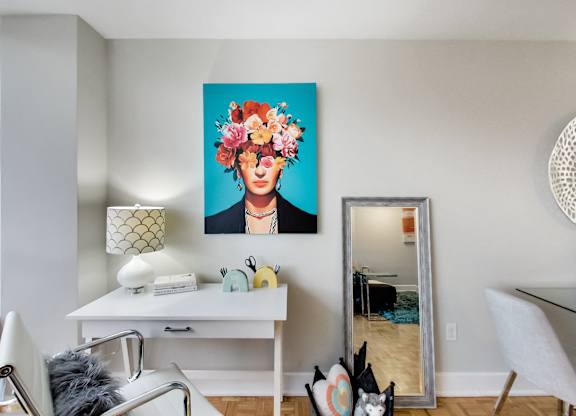 A room with a white desk and a painting of a woman with flowers in her hair.