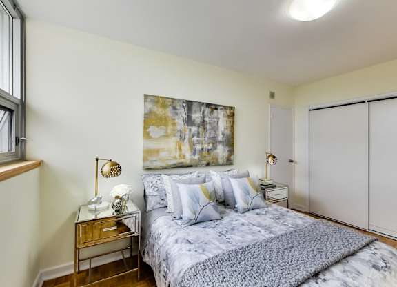 A bedroom with a bed, nightstand, and a painting on the wall.