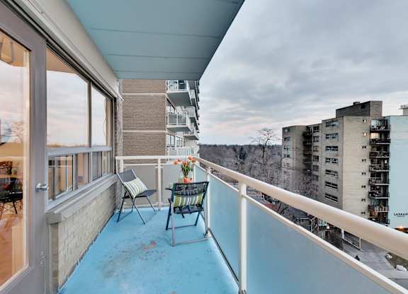 A balcony with a table and chairs overlooking a cityscape.