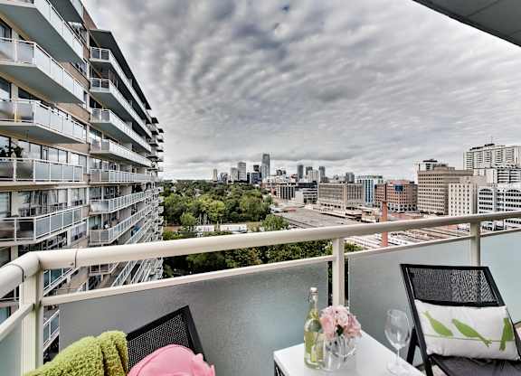 A balcony with a table set for two overlooks a cityscape.