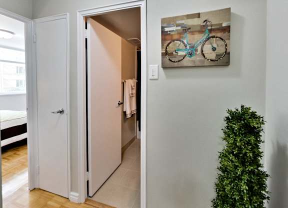 A white door is open to a hallway with a painting of a bike on the wall.