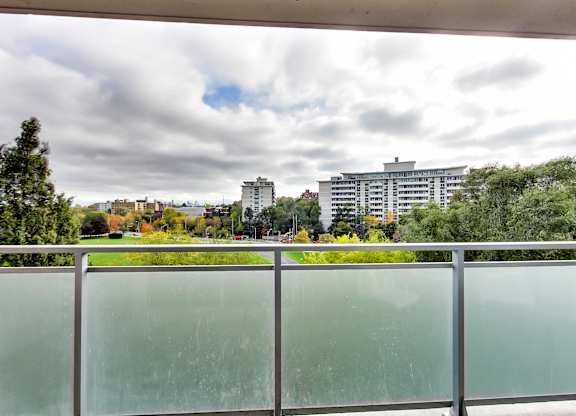 A view from a balcony looking out at a cityscape with buildings and trees.