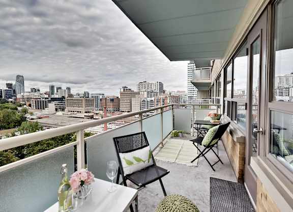 A balcony with a table and chairs overlooking a city skyline.