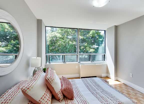 A bedroom with a large bed and a window overlooking trees.