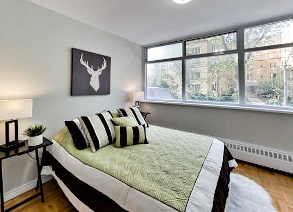 A bedroom with a bed, a deer head picture, and a window.