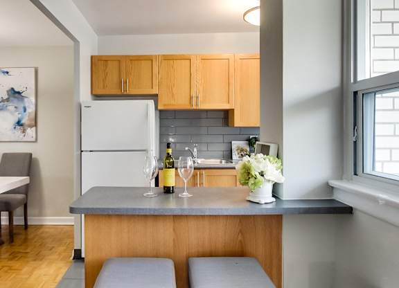 a kitchen with a counter with a bottle of wine and two stools