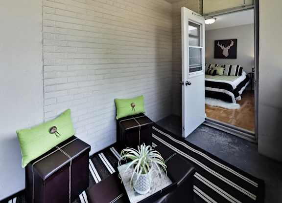 A room with a white brick wall and a bed with a black and white striped comforter.