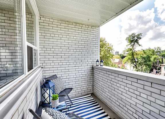 a balcony with a chair and a table and a brick wall